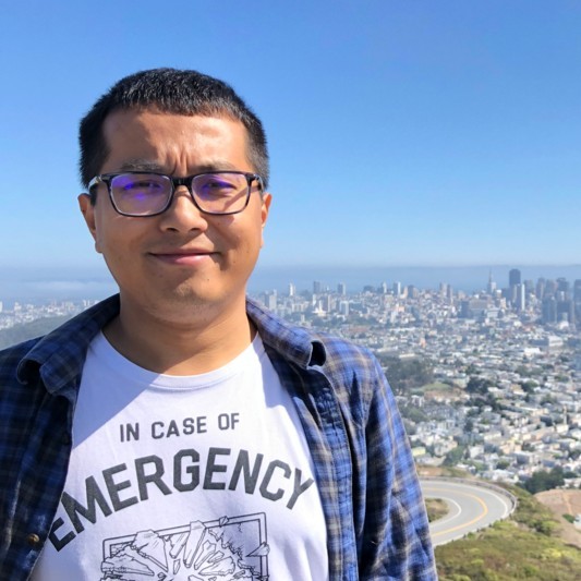 Lingyun Wang standing outdoors with a city view in the background.